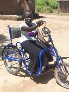 Picture of young girl in a tricycle which allows her to travel to school Photo SCIAF