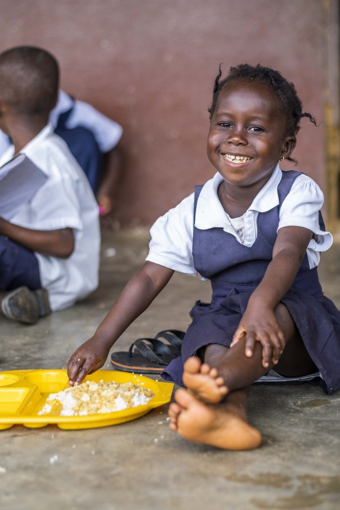 Mary's Meal appeal campaign image featuring a smiling girl eating lunch