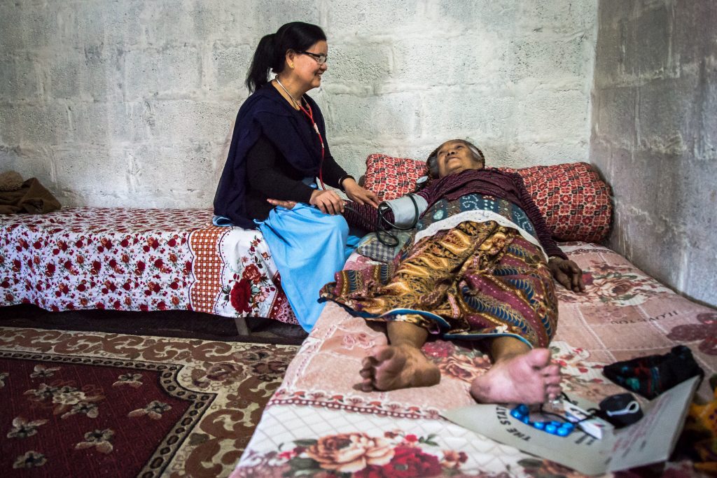 Palliative care nurse Purnamaya Gurung with the patient during one of her regular community visits
