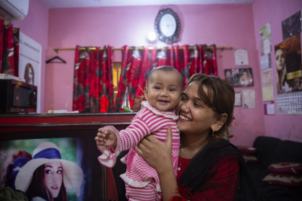 Sehrish Kiran holds her 6-month-old daughter Menahil at her salon that she has been running for the the past 3 years in Karachi, Pakistan