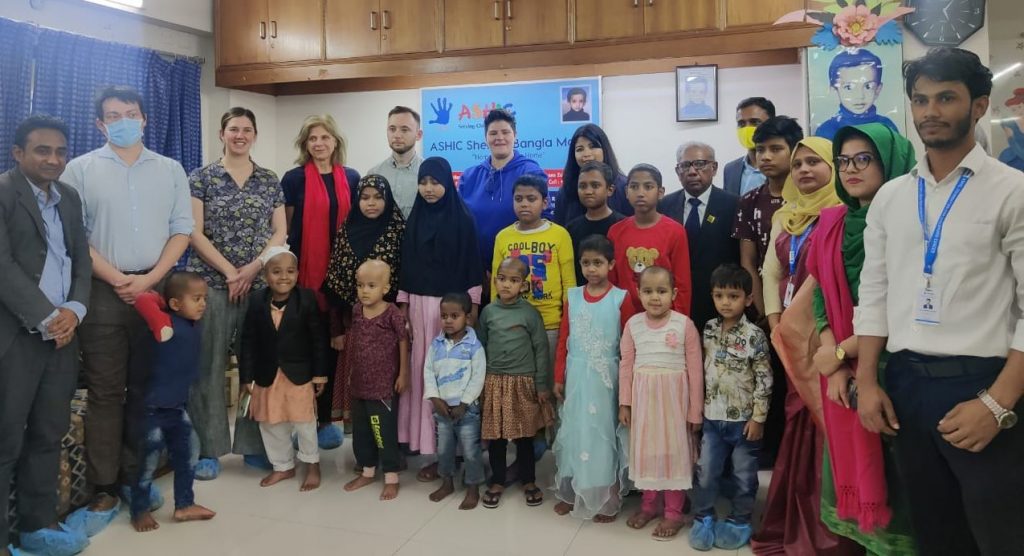 Women, men and children smile to camera in a hospital setting