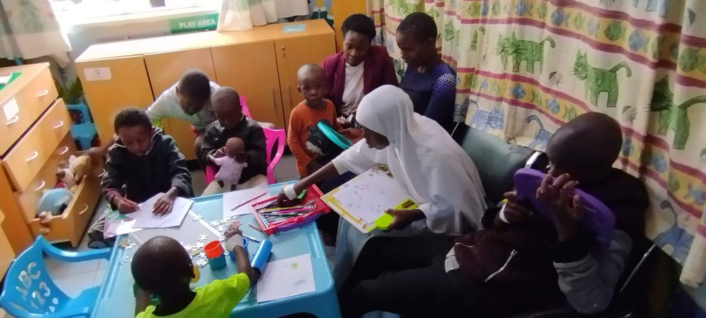 A woman and children sat in an area using crayons and paper to draw pictures 