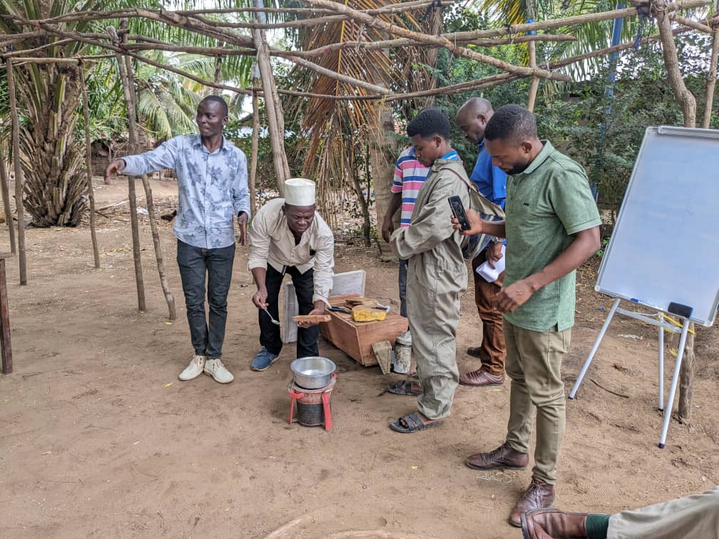 A group of people demonstrating how to use beeswax to attract honey bees