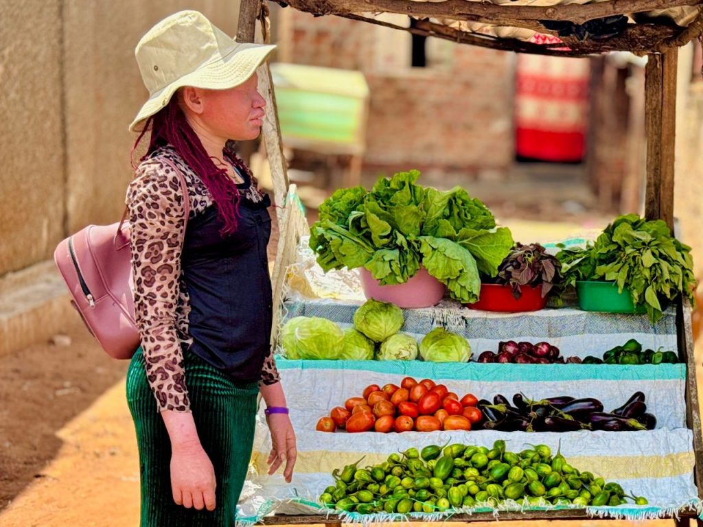 A woman stood next to her market stall of vegetables 
