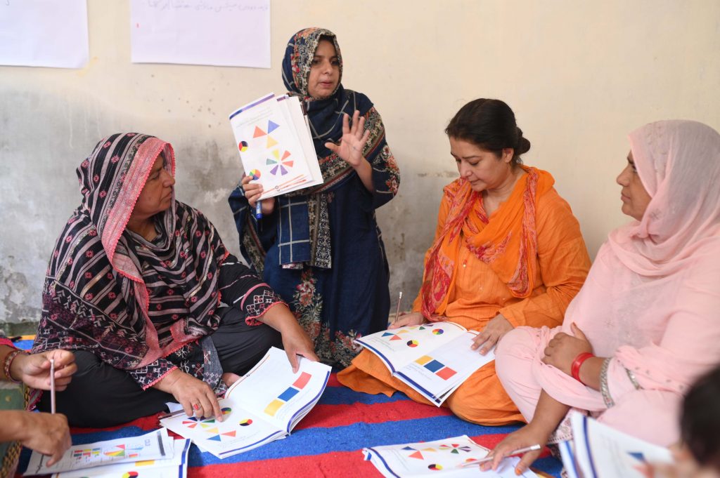 A group of women sat on the floor with workbooks