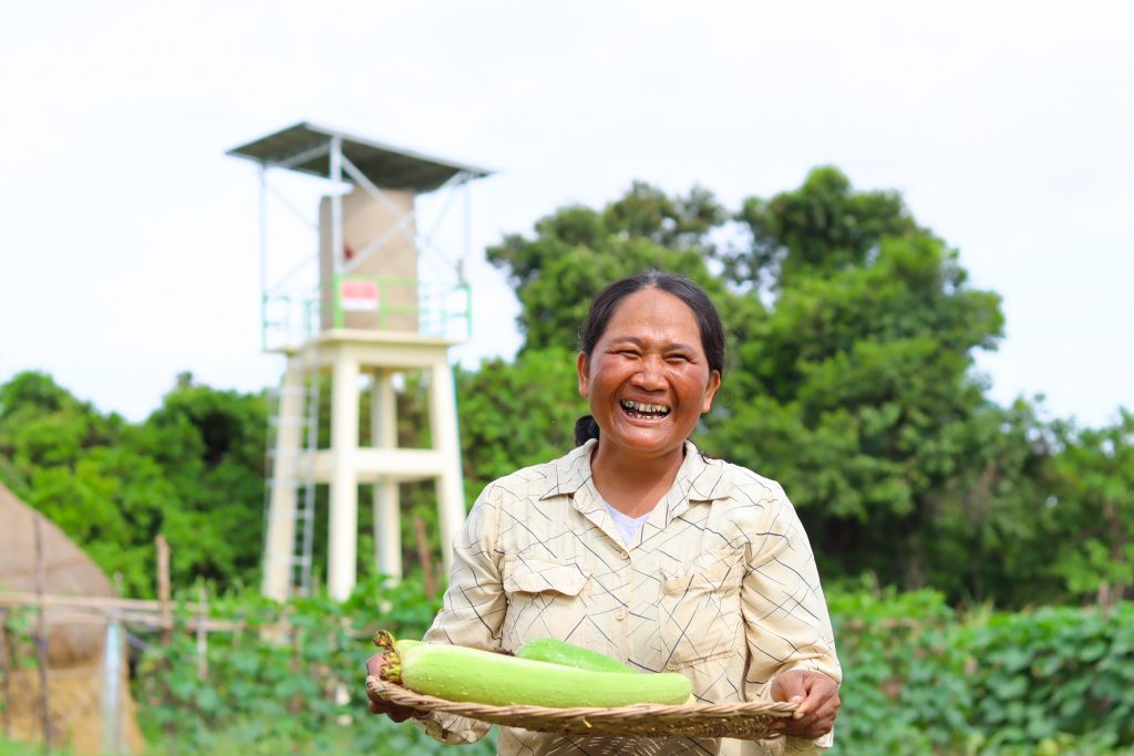 A woman stood in a field holding a vegetable