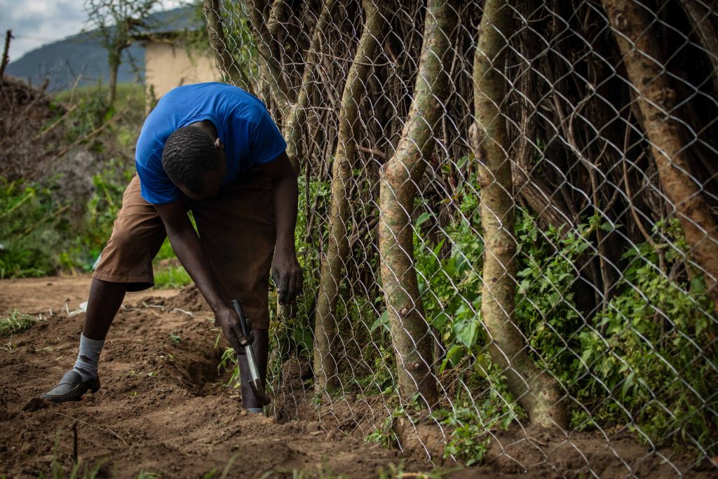 A man stood next to a wire fence and trees